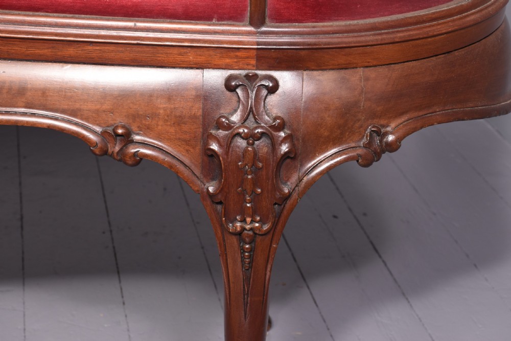 A large oval mahogany display cabinet featuring curved glass sides, red velvet lining, carved cabriole legs, and claw and ball feet. View VII