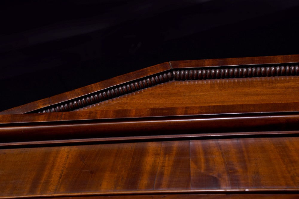 A George IV mahogany secretaire bookcase featuring arched astragal glazed doors, a fitted pull-out writing drawer with brass handles, and twin cupboard doors below. View V