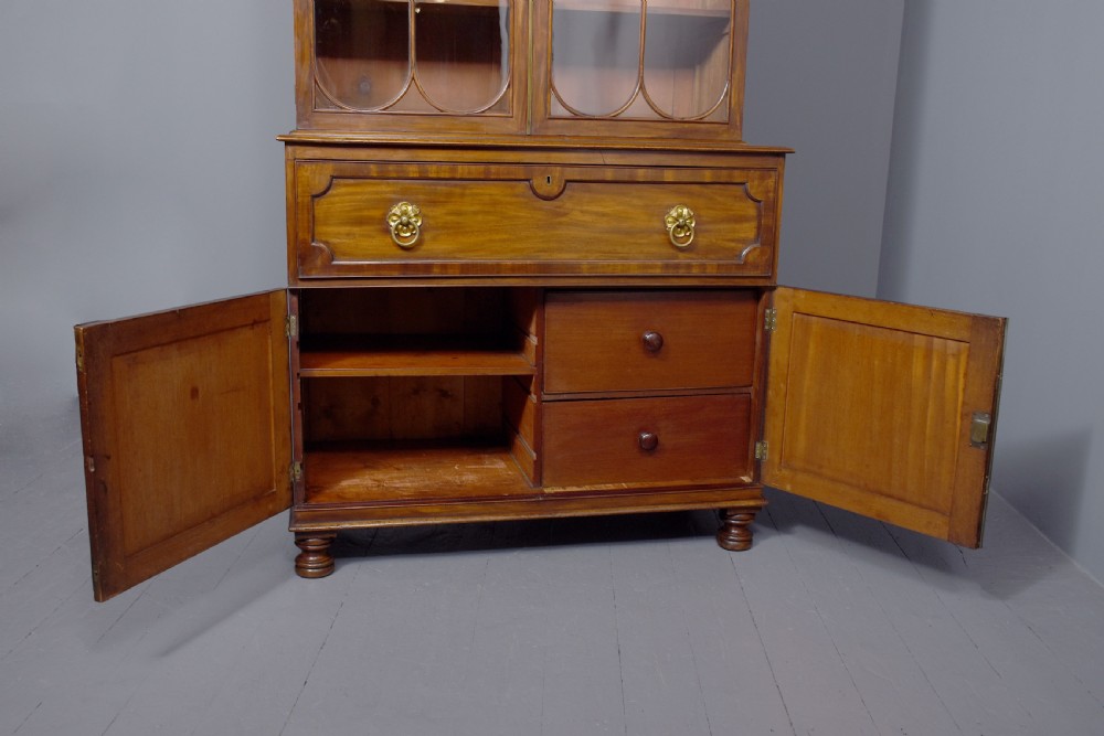 A George IV mahogany secretaire bookcase featuring arched astragal glazed doors, a fitted pull-out writing drawer with brass handles, and twin cupboard doors below. View IX