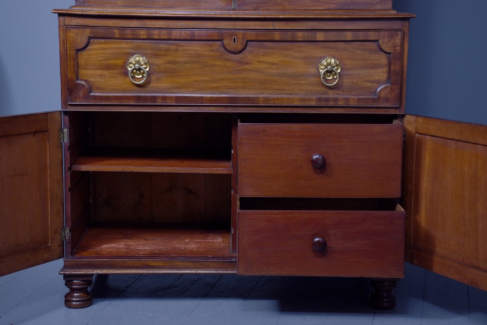 A George IV mahogany secretaire bookcase featuring arched astragal glazed doors, a fitted pull-out writing drawer with brass handles, and twin cupboard doors below. View X
