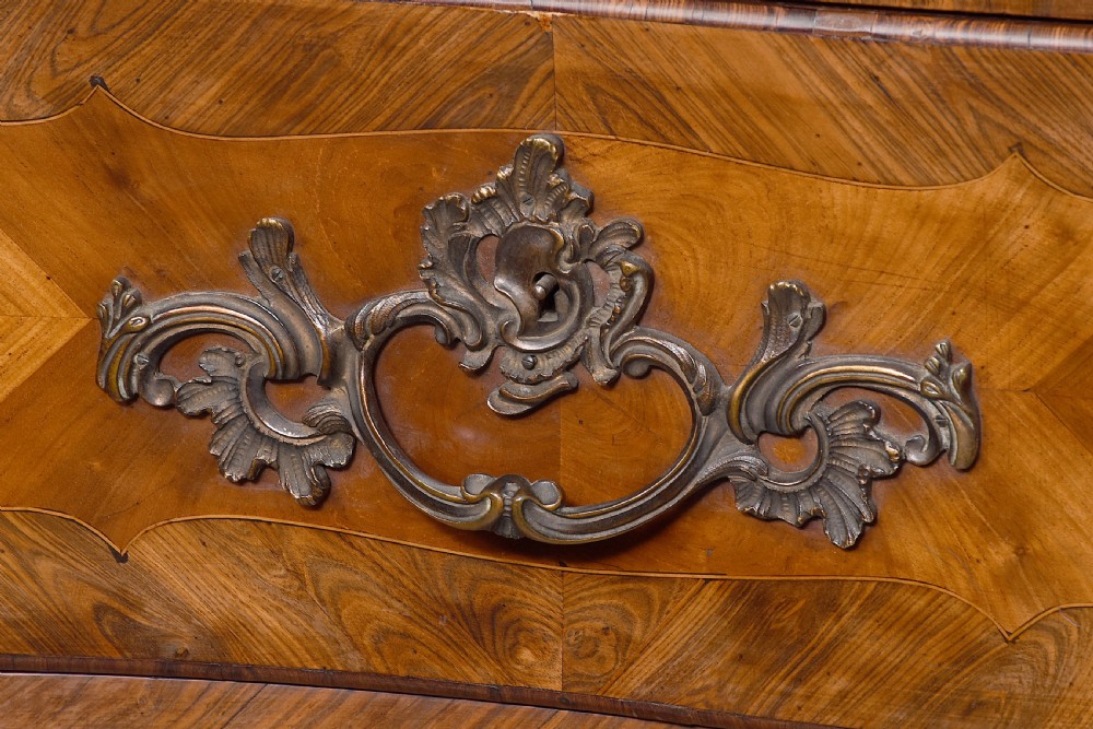 A Louis XV style bombee commode featuring a variegated marble top, geometric timber parquetry, three drawers, and ornate bronze handles. View VII
