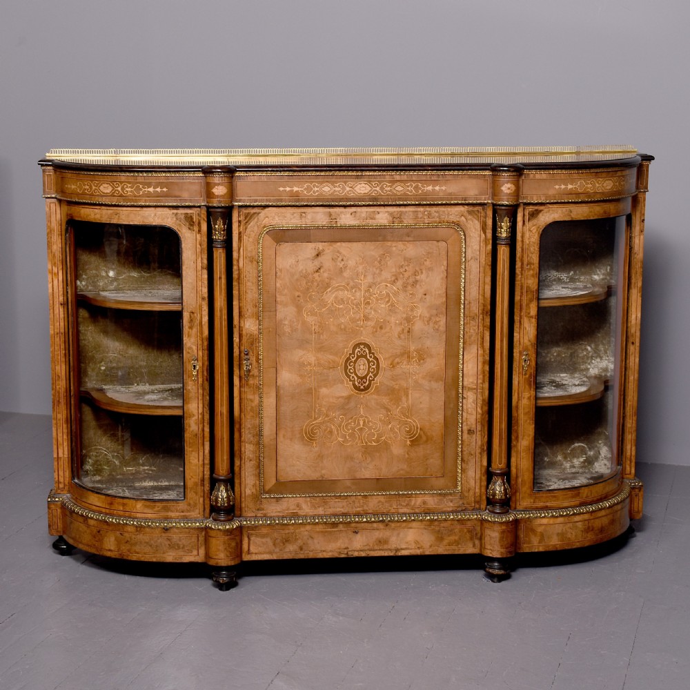 A Victorian burr walnut credenza featuring a central marquetry inlaid panel door flanked by two curved glazed display cupboards and gilt-bronze mounts.