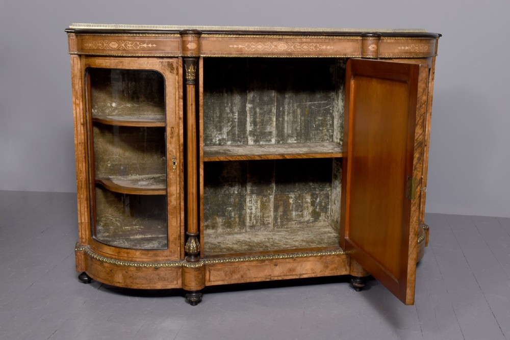 A Victorian burr walnut credenza featuring a central marquetry inlaid panel door flanked by two curved glazed display cupboards and gilt-bronze mounts. View X