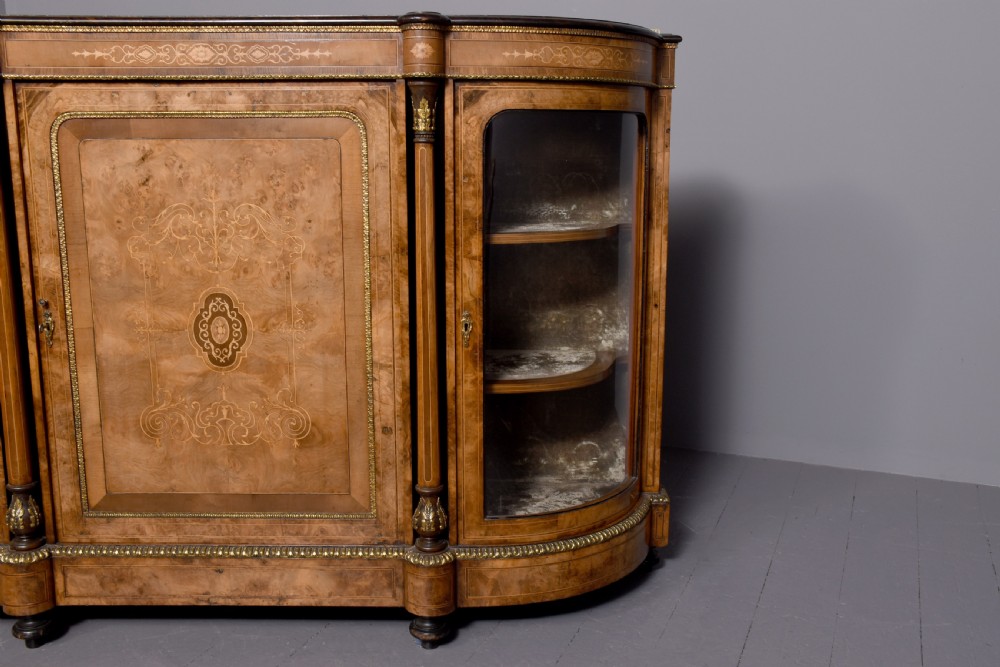 A Victorian burr walnut credenza featuring a central marquetry inlaid panel door flanked by two curved glazed display cupboards and gilt-bronze mounts. View XI