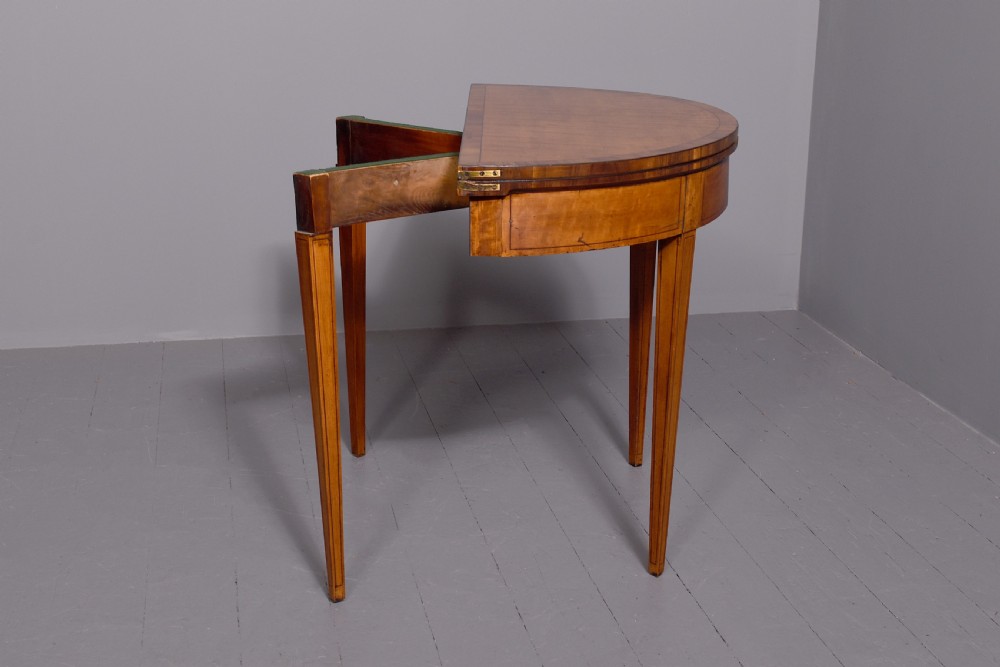 A late 18th-century George III semi-circular satinwood card table featuring crossbanded inlay borders and four square tapered legs. View II