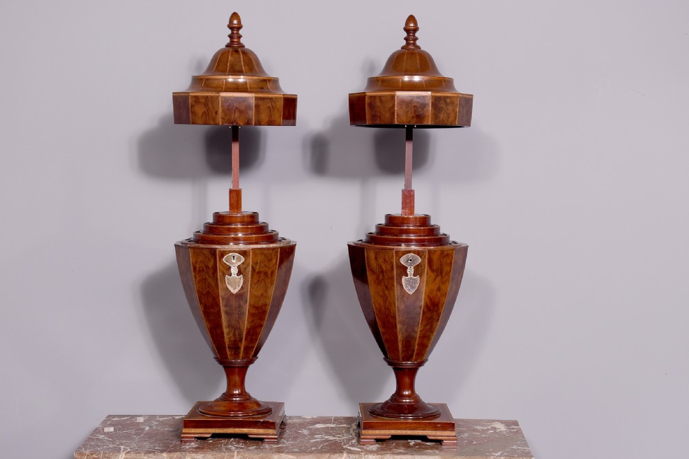 A pair of faceted mahogany cutlery urns featuring geometric stringing inlay, turned finials, and silver keyhole escutcheons on square pedestals. View IV