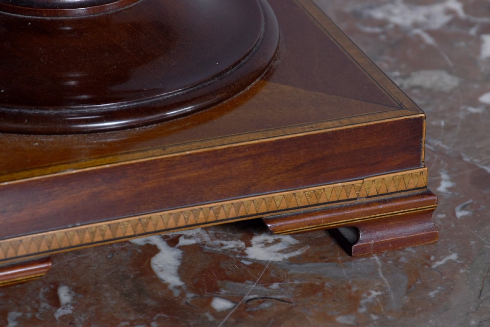 A pair of faceted mahogany cutlery urns featuring geometric stringing inlay, turned finials, and silver keyhole escutcheons on square pedestals. View V