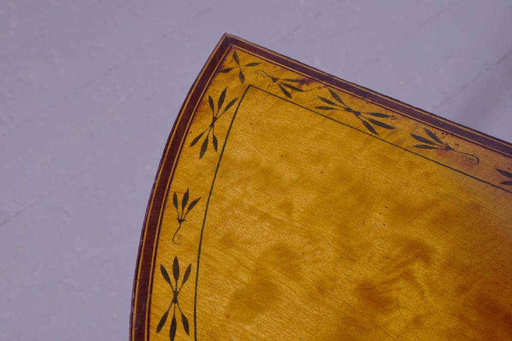 A George III demi-lune satinwood card table with painted decorative motifs, string inlay, and four square tapered legs. View IV