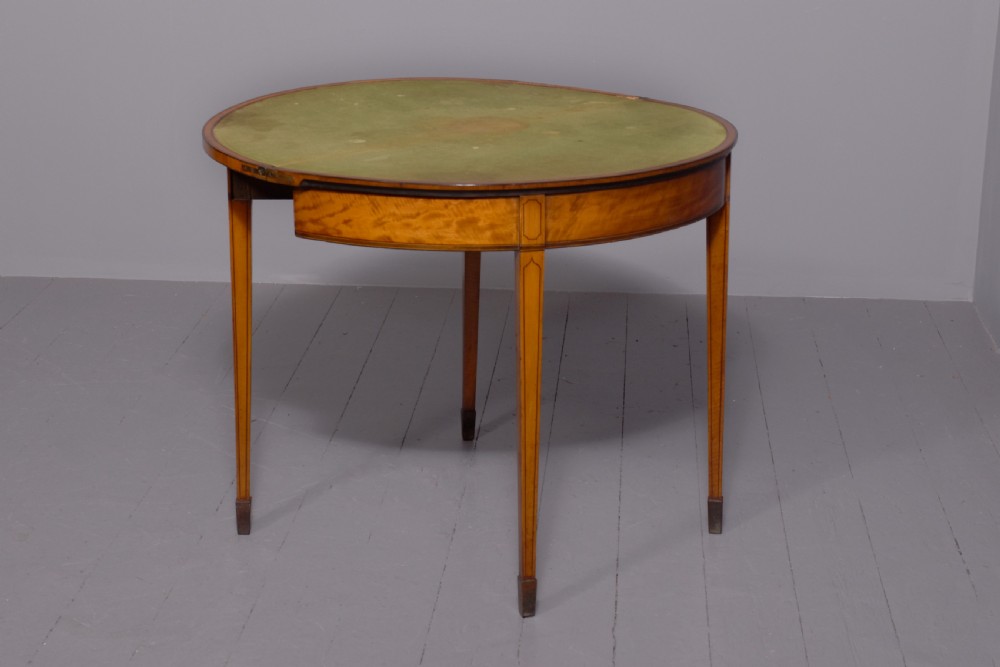 A George III demi-lune satinwood card table with painted decorative motifs, string inlay, and four square tapered legs. View VI