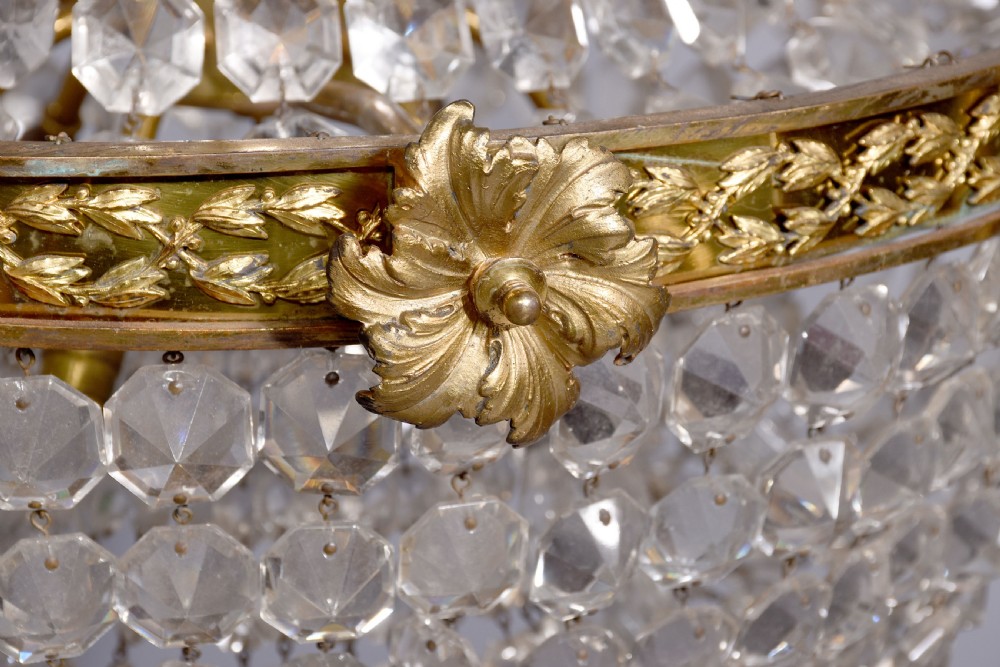 An Empire style brass and glass chandelier featuring a cascading tent of clear glass beads, decorative brass leaf mounts, and a lower rounded glass basket. View III