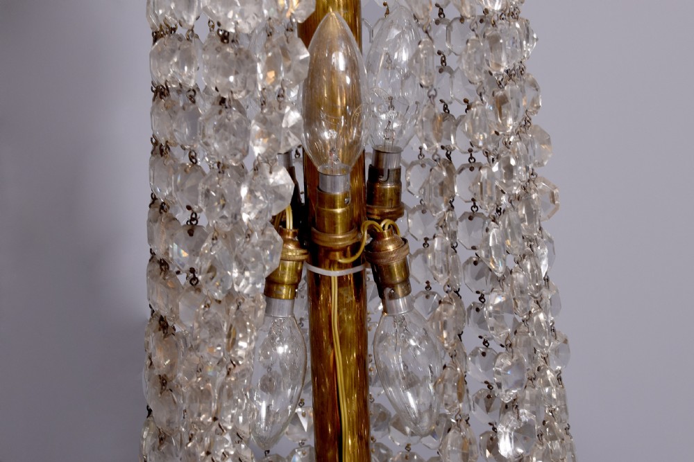 An Empire style brass and glass chandelier featuring a cascading tent of clear glass beads, decorative brass leaf mounts, and a lower rounded glass basket. View IX