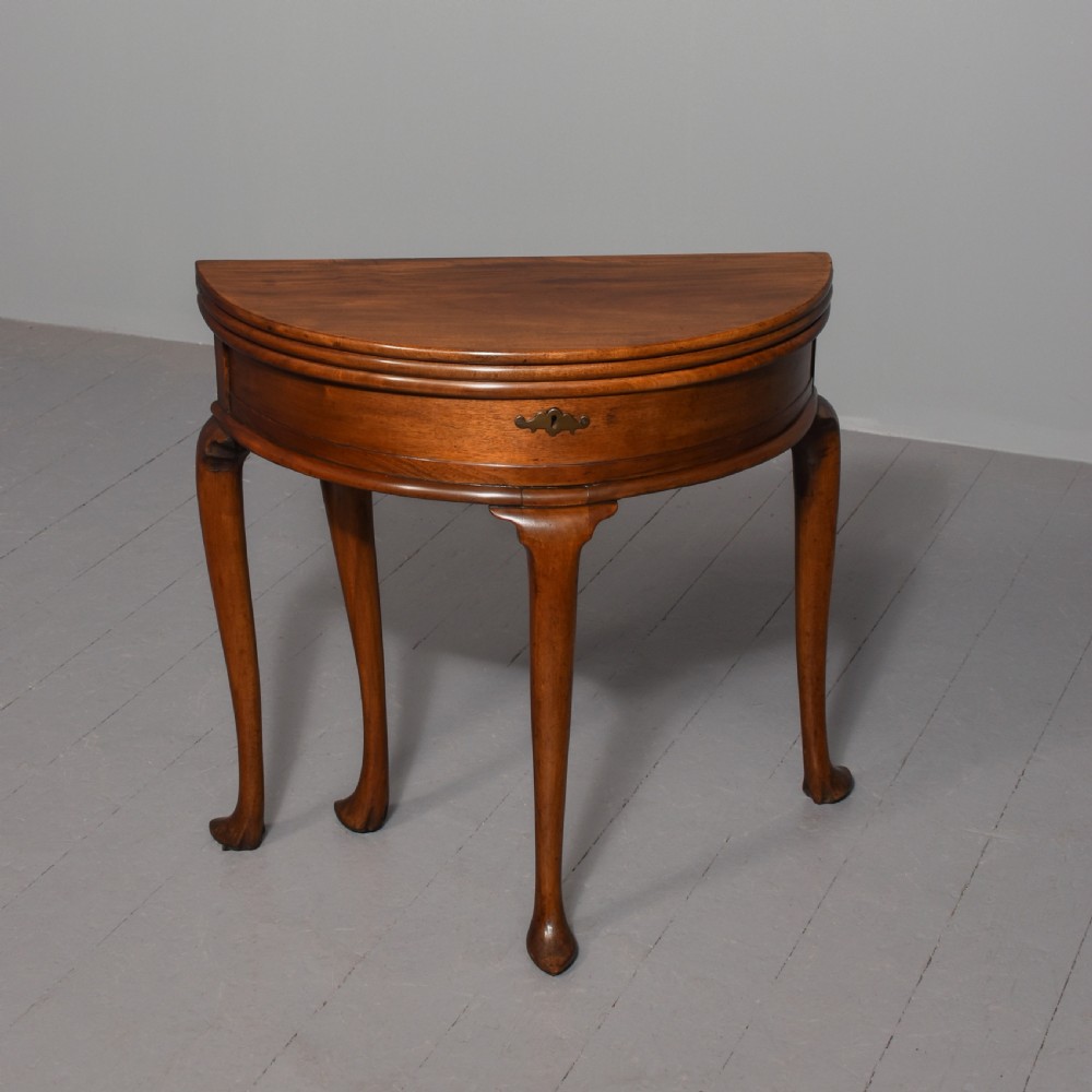 A George III demilune mahogany triple-top games table with cabriole legs, pad feet, and a central brass escutcheon on the apron.