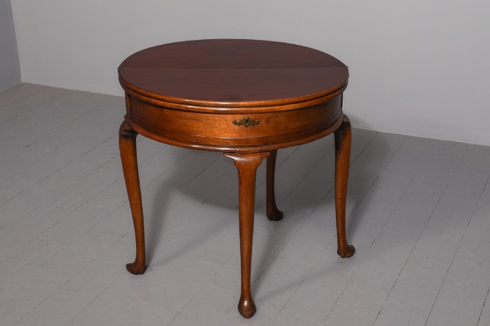 A George III demilune mahogany triple-top games table with cabriole legs, pad feet, and a central brass escutcheon on the apron. View II
