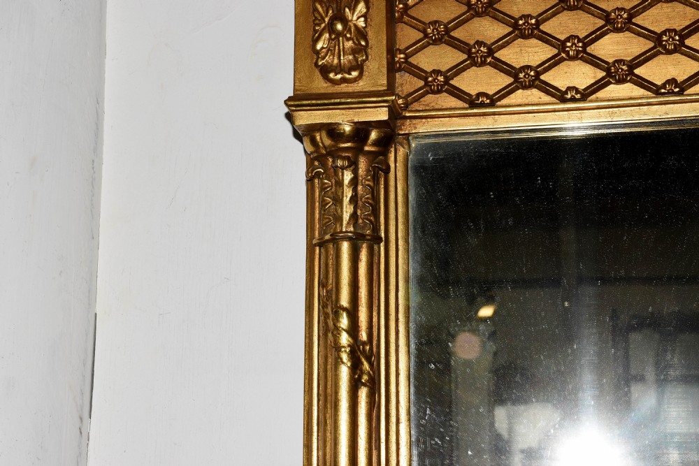 A large horizontal Regency gilded overmantel mirror featuring a ball-moulded cornice, central drapery swag motif, lattice frieze, and side pilasters. View III