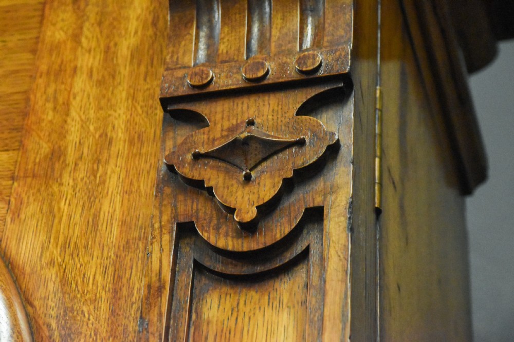 A large Mid-Victorian carved wooden glazed bookcase featuring four upper cabinet doors with arch tracery and four lower panelled cupboard doors topped with decorative finials. View IX