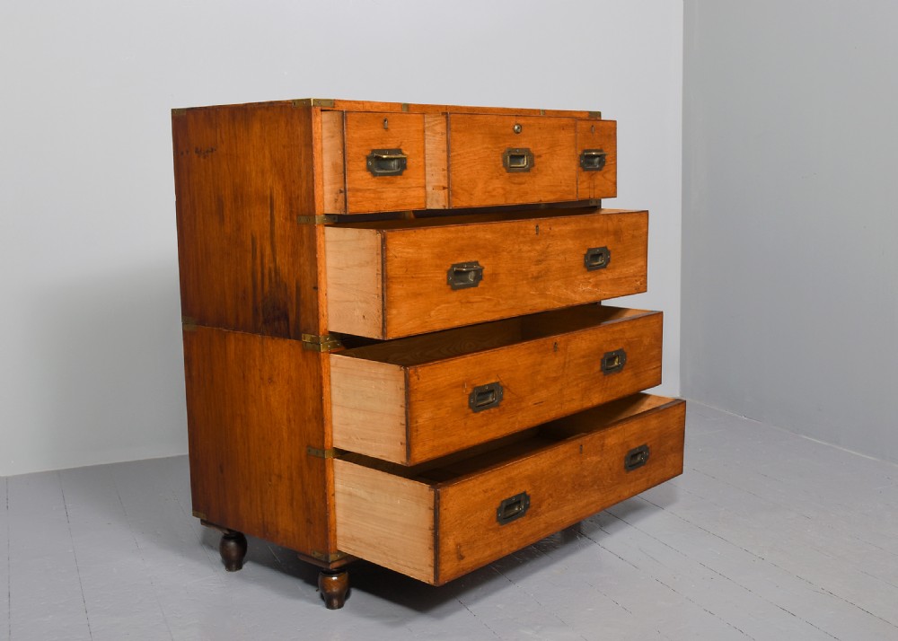 A nineteenth-century two-part teak military campaign chest of drawers featuring flush brass handles, protective brass corner brackets, and turned feet. View VII