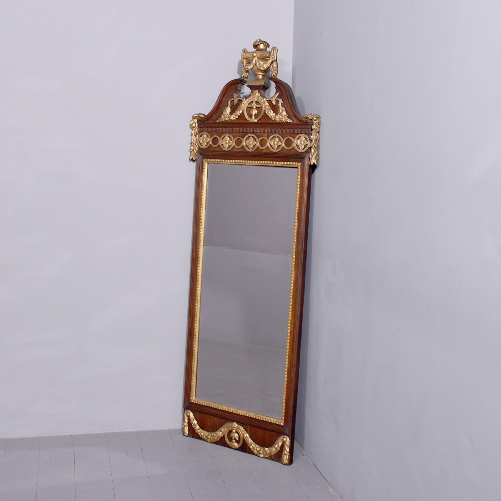 A tall Swedish Gustavian mahogany pier mirror featuring an urn finial cresting and gold gilt decorative swags.