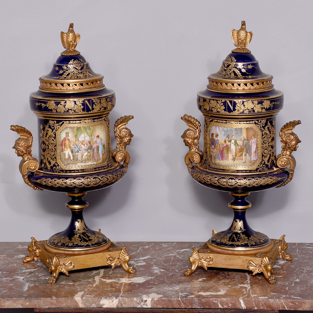 A pair of French cobalt blue porcelain lidded urns with intricate gilding, hand-painted Napoleonic historical scenes, and gilt bronze helmeted bust handles topped with eagle finials. View IV