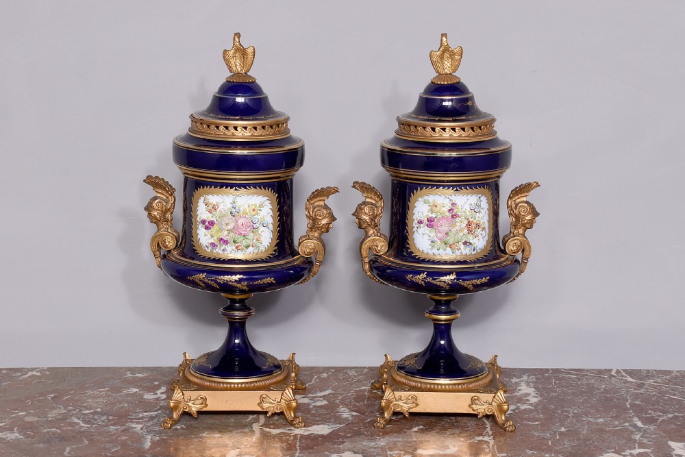 A pair of French cobalt blue porcelain lidded urns with intricate gilding, hand-painted Napoleonic historical scenes, and gilt bronze helmeted bust handles topped with eagle finials. View XII