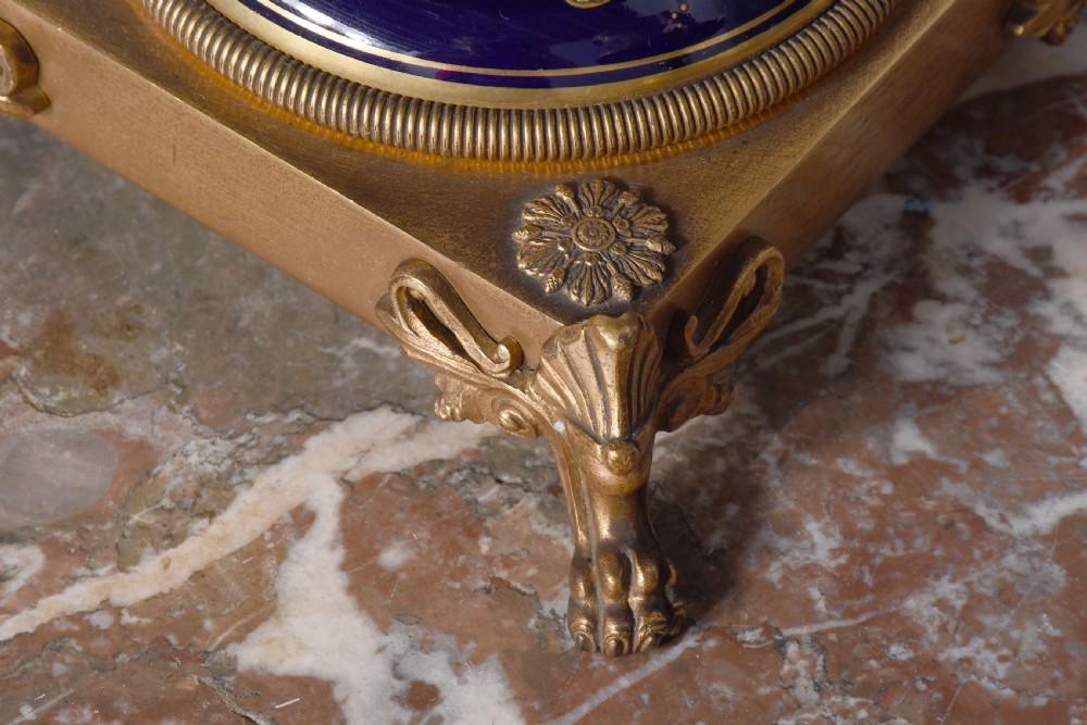 A pair of French cobalt blue porcelain lidded urns with intricate gilding, hand-painted Napoleonic historical scenes, and gilt bronze helmeted bust handles topped with eagle finials. View XV