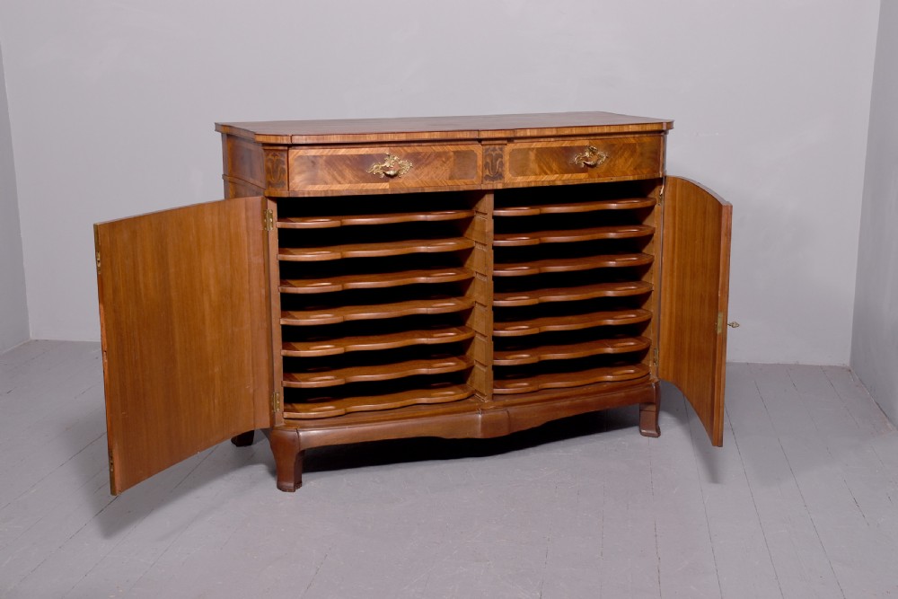 A two-door wooden folio cabinet with dark marquetry scroll inlay, upper drawers with ornate brass handles, and short shaped legs. View VIII