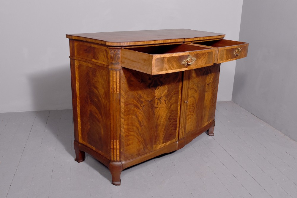 A two-door wooden folio cabinet with dark marquetry scroll inlay, upper drawers with ornate brass handles, and short shaped legs. View X