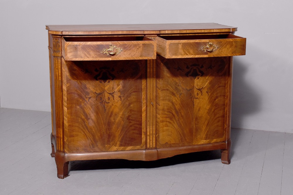 A two-door wooden folio cabinet with dark marquetry scroll inlay, upper drawers with ornate brass handles, and short shaped legs. View XI