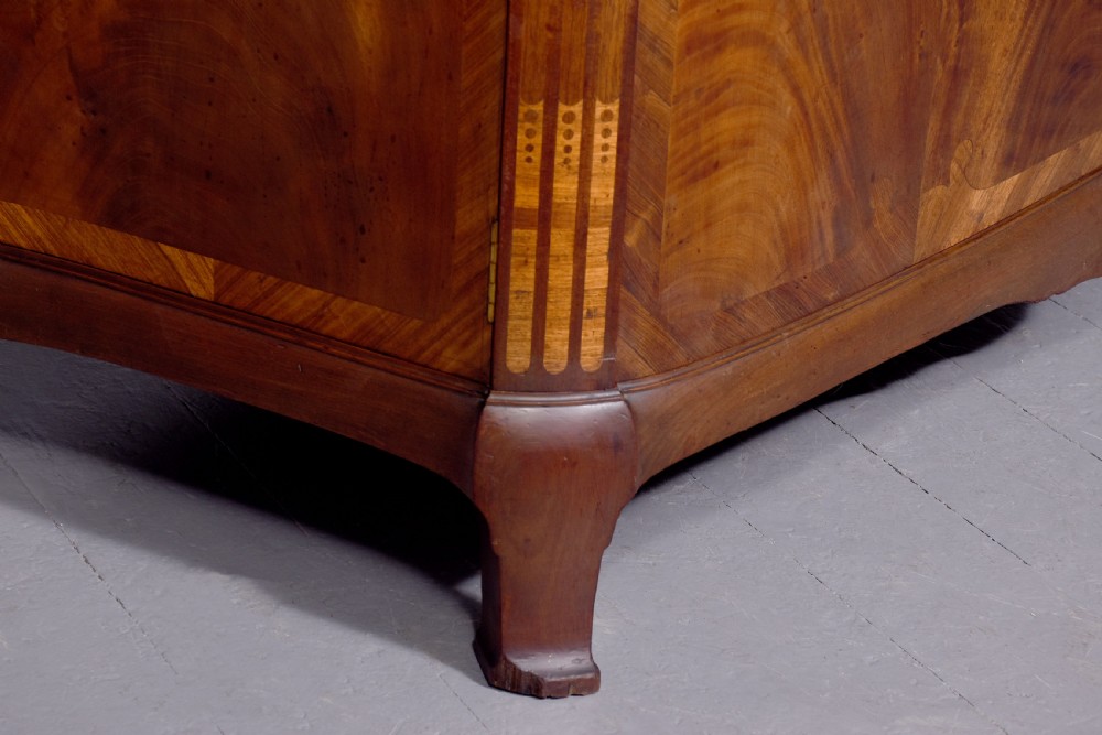 A two-door wooden folio cabinet with dark marquetry scroll inlay, upper drawers with ornate brass handles, and short shaped legs. View XII
