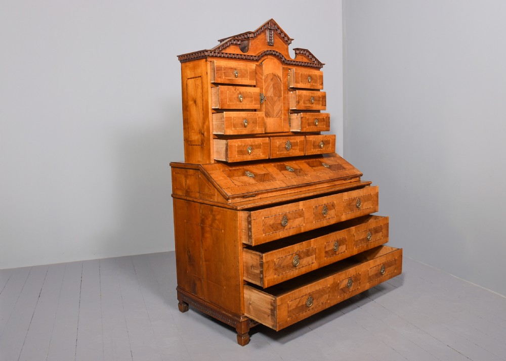 An 18th-century walnut bureau bookcase featuring geometric marquetry, a slant-front writing surface, multiple drawers, and an architectural top pediment. View X