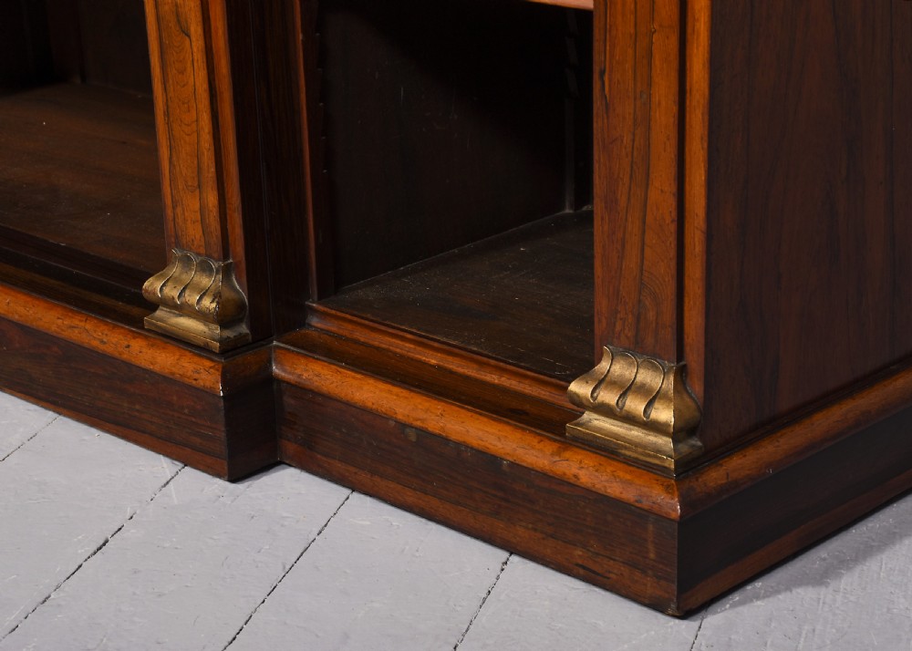 An antique open breakfront bookcase constructed from dark rosewood with gilded carved capitals and filled with leather-bound books. View V