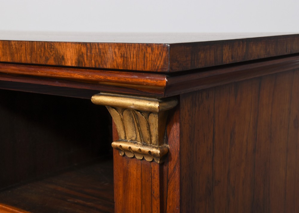 An antique open breakfront bookcase constructed from dark rosewood with gilded carved capitals and filled with leather-bound books. View VII