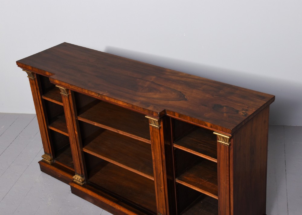 An antique open breakfront bookcase constructed from dark rosewood with gilded carved capitals and filled with leather-bound books. View VIII