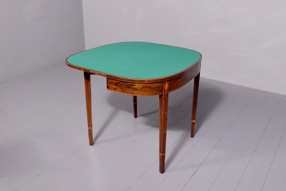 A George III rosewood fold-over card table displaying a green baize interior, satinwood stringing, and square tapered legs.