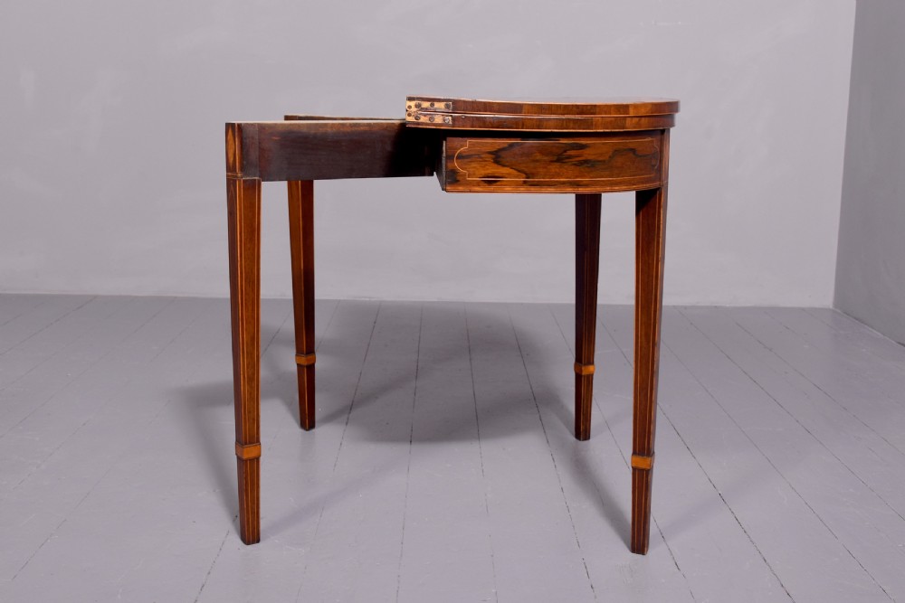 A George III rosewood fold-over card table displaying a green baize interior, satinwood stringing, and square tapered legs. View VI
