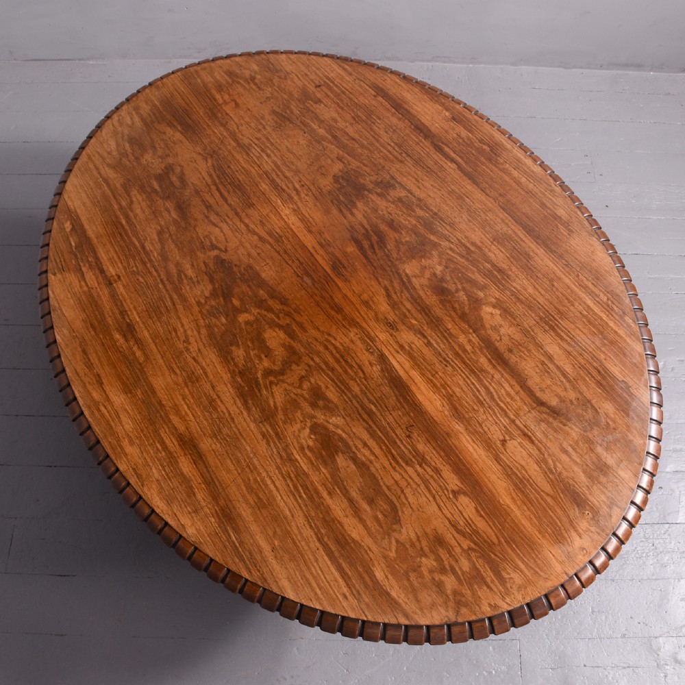 A circular George IV rosewood breakfast table featuring a carved edge, a spiral column pedestal, and a quadruped scrolled base with brass castors. View V