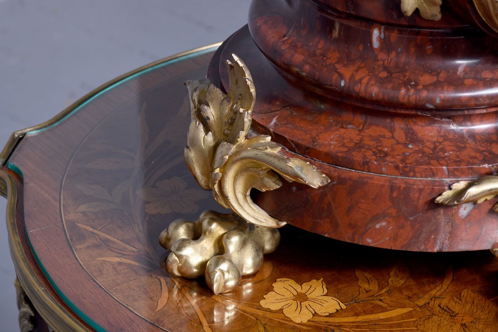 A French Neoclassical style mantel clock featuring a cylindrical rouge marble body with gilt bronze floral swags, a top urn finial, and paw feet. View VIII