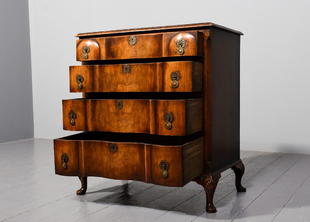 A George II style walnut chest of drawers featuring a contoured front, four drawers with brass handles, and cabriole legs. View II