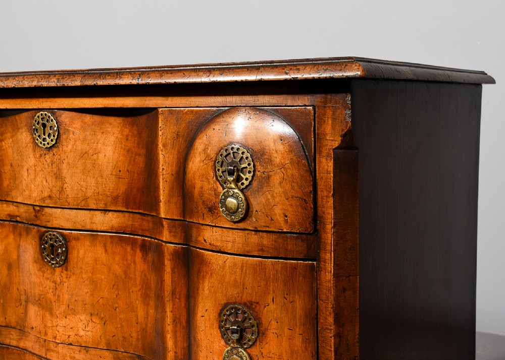 A George II style walnut chest of drawers featuring a contoured front, four drawers with brass handles, and cabriole legs. View IV