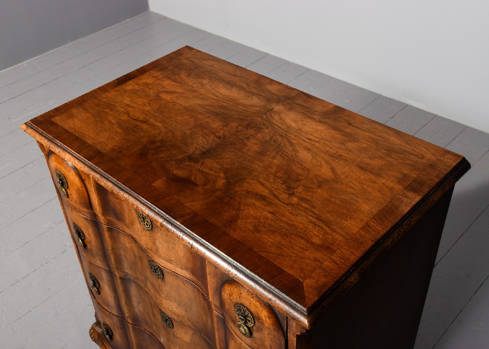 A George II style walnut chest of drawers featuring a contoured front, four drawers with brass handles, and cabriole legs. View VII