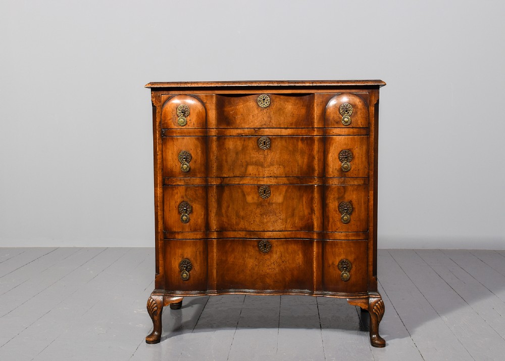 A George II style walnut chest of drawers featuring a contoured front, four drawers with brass handles, and cabriole legs. View VIII