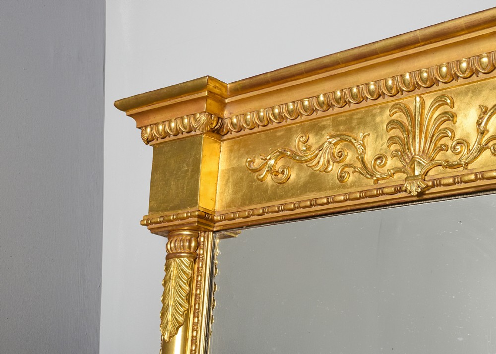 A tall Regency gilded pier mirror featuring a carved architectural cornice, side columns with leaf motifs, and a central classical frieze. View VII