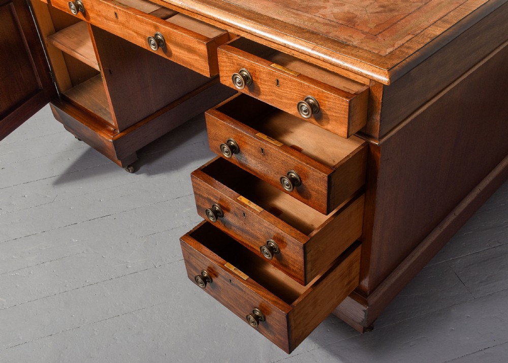 A Georgian style mahogany partners desk featuring a leather writing top, multiple drawers with brass turned knobs, and a pedestal base on castors. View III