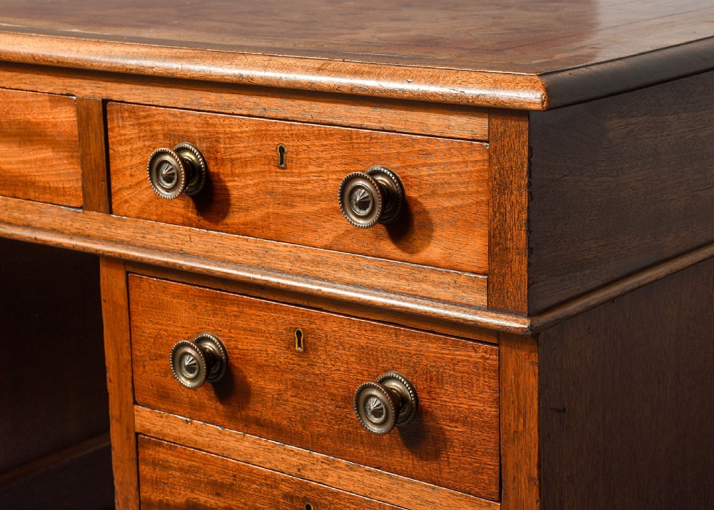 A Georgian style mahogany partners desk featuring a leather writing top, multiple drawers with brass turned knobs, and a pedestal base on castors. View V