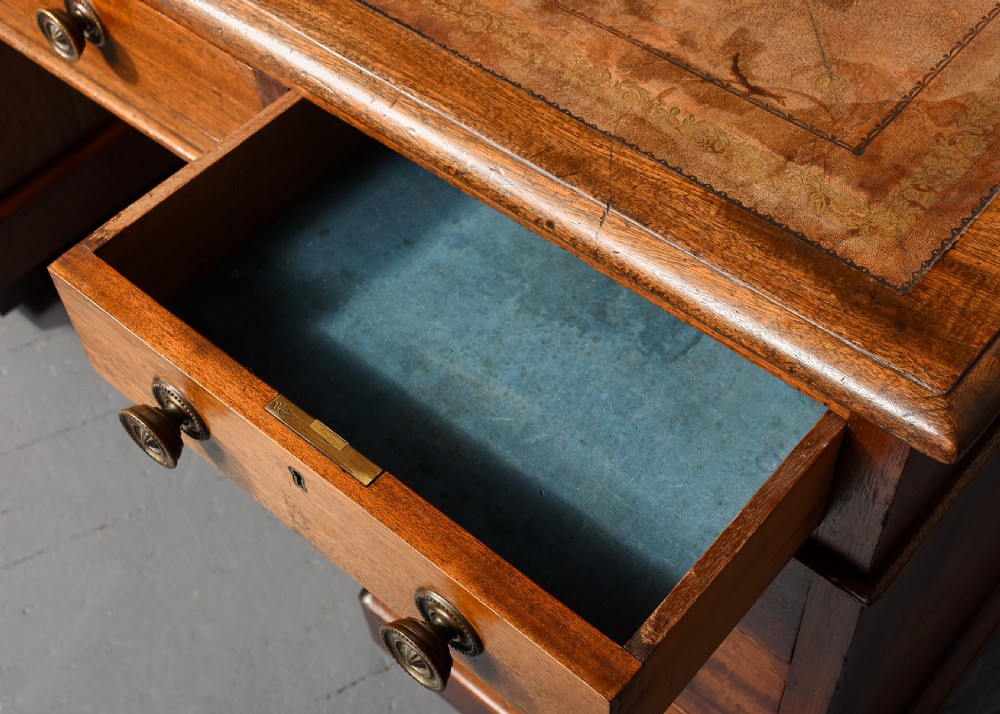 A Georgian style mahogany partners desk featuring a leather writing top, multiple drawers with brass turned knobs, and a pedestal base on castors. View XI