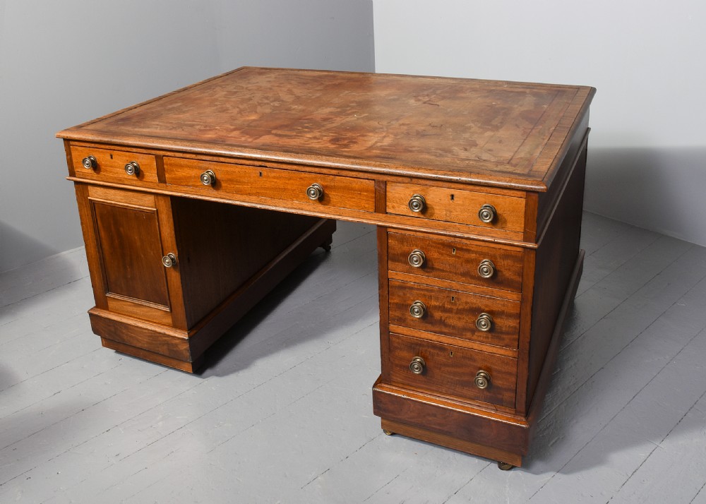 A Georgian style mahogany partners desk featuring a leather writing top, multiple drawers with brass turned knobs, and a pedestal base on castors. View XII