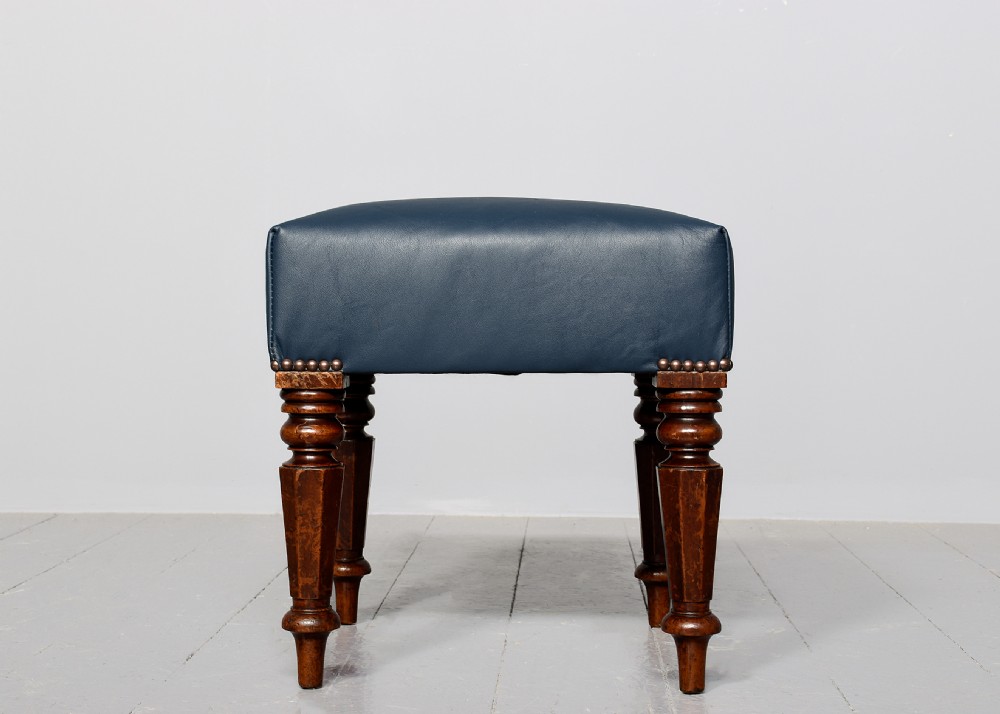 A William IV mahogany footstool featuring turned faceted legs and dark blue leather upholstery trimmed with brass studs. View III