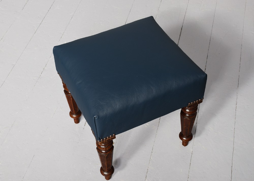 A William IV mahogany footstool featuring turned faceted legs and dark blue leather upholstery trimmed with brass studs. View IV