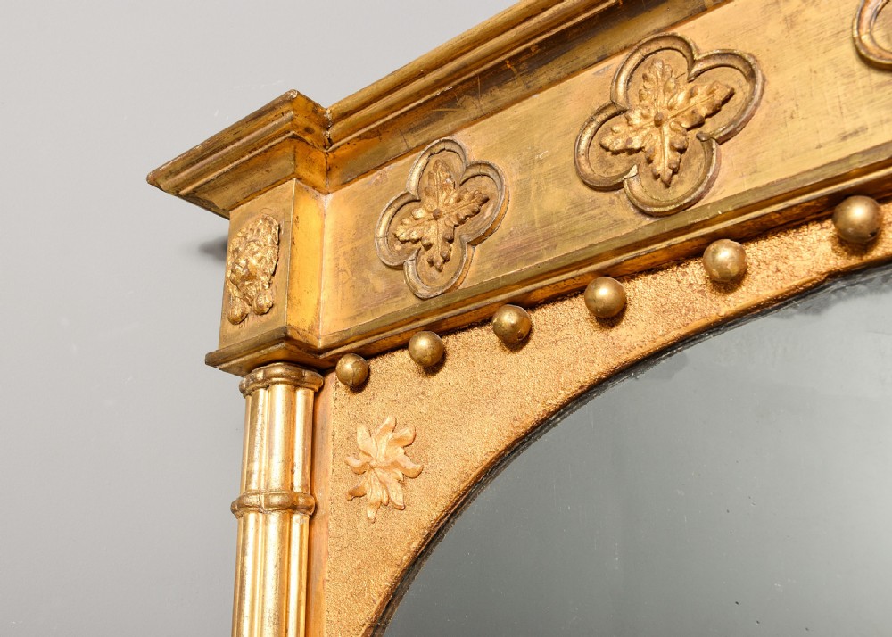 A rectangular Regency period giltwood pier mirror featuring an arched inner frame, fluted side columns, ball moulding, and decorative rosette motifs. View III