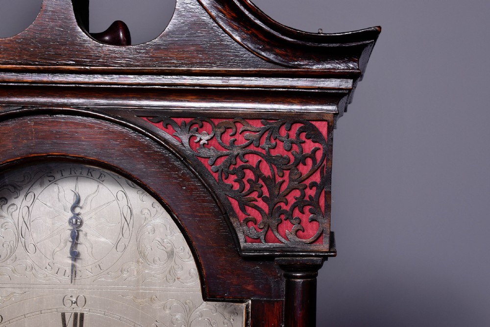 A George III dark mahogany longcase grandfather clock featuring a swan-neck pediment, brass finial, and an engraved brass arch dial. View III