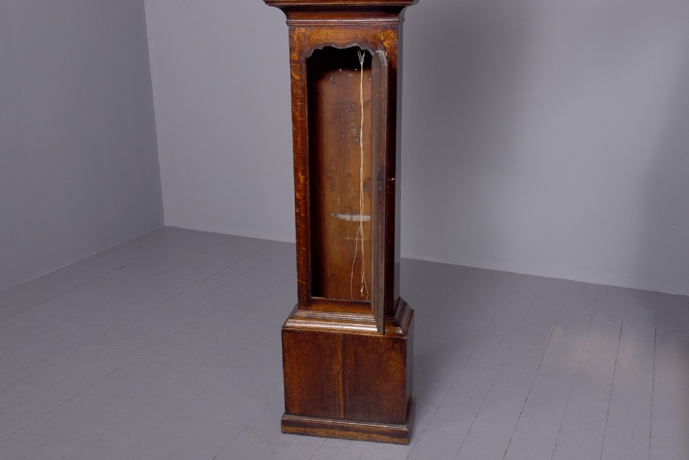 A George III dark mahogany longcase grandfather clock featuring a swan-neck pediment, brass finial, and an engraved brass arch dial. View VI
